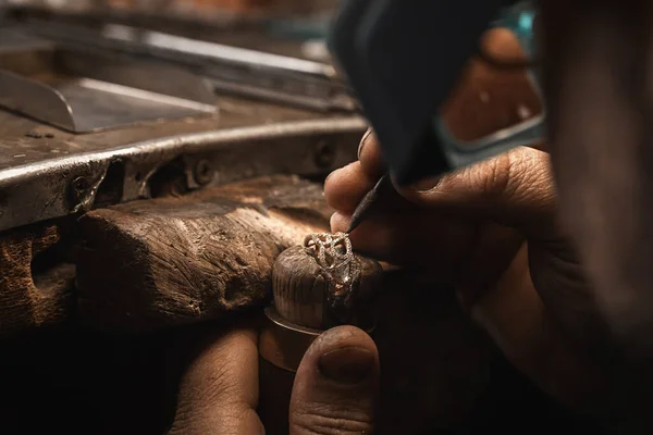 Close up of a goldsmiths hand making a gold or silver ring or a diamond using goldsmiths tools. Making ring with diamonds