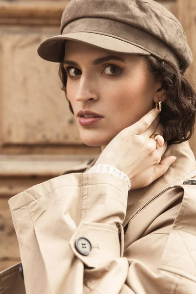 Stock image Young beautiful girl, brunette with curly hair. Dressed in a stylish beige trench coat and cap.