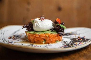 Çiğ somon, avokado mor soğan salatası ve siyah tabakta servis edilen yemek halkası. Ahşap arkaplan