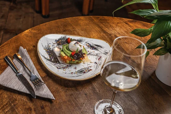 Çiğ somon, avokado mor soğan salatası ve siyah tabakta servis edilen yemek halkası. Ahşap arkaplan