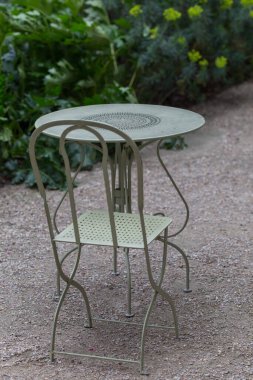 Boş metal sandalyeler ve bahçede bir masa.