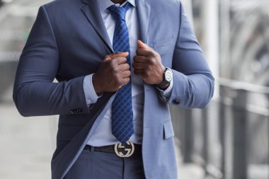 Kol saatinin cebinde kravatını düzelten genç işadamının kırpık manzarası..