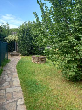 Çitleri olan bir bahçe ve küçük bir taş ev.