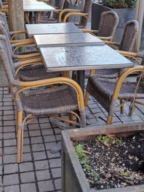 Bahçede beyaz ve siyah sandalyeli boş masalar.