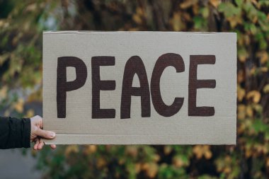 Pankartla yapılan savaşa karşı protesto. Yazılı mesaj. Barış, sonbahar ağacı.