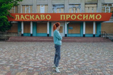 Bayan bomba patlamasından sonra köydeki hasarlı ve tahrip edilmiş okulun önünde duruyor. Girişte 