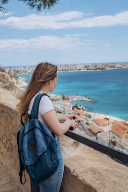 Kaygısız genç turist kadın Akdeniz 'deki Harbour, Santa Barbara Kalesi' nde deniz manzarasını seyrediyor. Alicante. İspanya 'da yaz tatili. Mavi sularda nefes kesici panoramik manzaranın tadını çıkar.