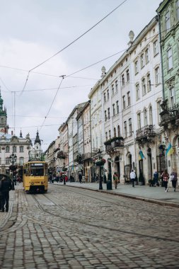 Lviv, Ukrayna - 13 Mayıs 2023: Lviv, Batı Ukrayna 'da sokak sahnesi, kaldırımın yanındaki geleneksel binalar. Büyüleyici bir mimari, tramvay ve dışarıda yürüyen insanlar. Eski şehir merkezi