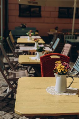 Boş masaları olan bir sokak kafesi. Çiçek vazoları masalarda ve eski sandalyelerde. Kafe restoranının dışında. Çiçekli kafe sehpası olan rahat bir cadde. Turizm tatili kavramı