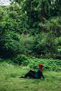 Beyaz kadın, Brera botanik bahçesinde çimlerin üzerinde oturuyor. Akademi kompleksinin bir parçası, Milan şehir merkezi, İtalya, dinleniyor, düşünüyor. Yazın parkta dinlenmek. Boşluğu kopyala