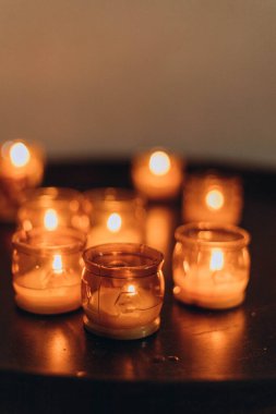 Paskalya mumlarının gece yanan altın mum ışığının resmi. Karanlık bir kilisede parlayan Lampion mumları. Duygusal bir ruh hali. Çok sayıda yanan mum sığ alan derinliğinde