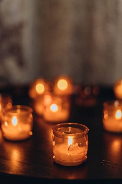 Paskalya mumlarının gece yanan altın mum ışığının resmi. Karanlık bir kilisede parlayan Lampion mumları. Duygusal bir ruh hali. Çok sayıda yanan mum sığ alan derinliğinde