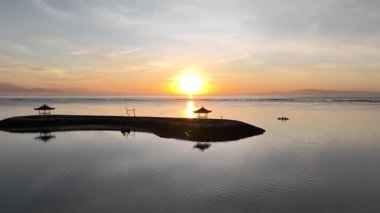 Altın gün doğumu, sakin okyanus dalgalarını ve kumlu kıyıları aydınlatır. Yukarıdan bir dron tarafından yakalanır..