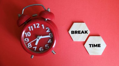 Üzerinde kelime kırma zamanı olan bir yapbozun yanında duran siyah bir çalar saat.