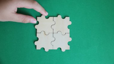 Yeşil arka planda yapbozun bir parçasını tutan el.