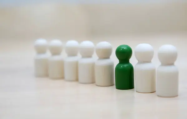 Birçok ahşap insan figüründe yeşil figür. Bireysellik, benzersizlik ve farklılık kavramı