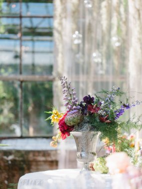 Enginar buketi, delfinyum, anturyum, gümüş bir vazoda iris. Sera düğün dekoru.