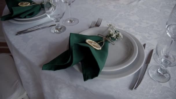 結婚式の装飾 結婚式の日のイベント組織テーブルの設定の装飾 美しい宴会テーブルを提供しています 白いプレート 緑のナプキン ガラスグラスとレモンとラコニックテーブルの設定 — ストック動画