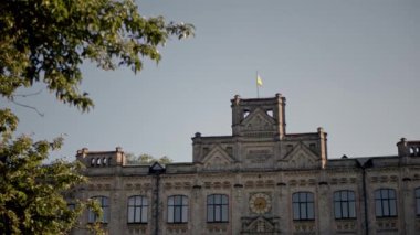 Ukrayna bayrağı antik binanın çatısında dalgalanıyor. Önünde Ukrayna bayrakları olan Kyiv Politeknik Enstitüsü 'nün cephesi..