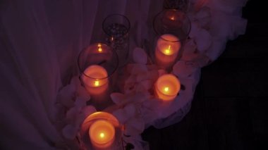 Bir dizi yanan beyaz mum, vazolarda mumlar. Mumlarla dekoratif dekorasyon. Karanlıkta mumsuz titreşimler..