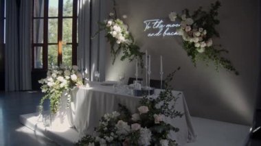 Şölen salonunda, başkanlık makamının düğün süsü. Yeni evliler için masa servisi. Romantik çiçek dekoru ve üzerinde yazı olan neon tabela..