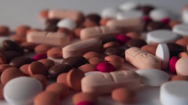 Beyaz arka plana bir sürü hap döküldü. Farklı haplar düşüyor. Bir sürü hap, ilaç, antibiyotik, vitamin. Sağlık, ilaç endüstrisi, tıp konsepti. Düşük açı. Yavaş çekim.