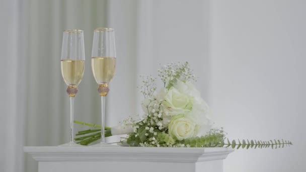 Två Glas Champagne Och Brudbukett Ljus Bakgrund Närbild Två Bröllopsglas — Stockvideo