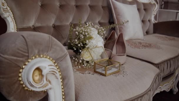 結婚式の朝だった 結婚式の詳細 美しい結婚式の花束は結婚指輪とベビーベッドのソファーの花嫁の靴に横たわっています スローモーション — ストック動画
