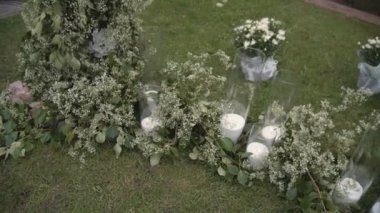 Düğün dekoru. Düğün töreni alanı. Kemer çiçeklerle süslenmiş. Şenlik dekorunun bir parçası, mumlu bir kompozisyon. Yavaş çekim.