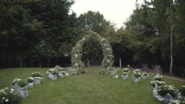 Yeşil doğal arka planda beyaz çiçeklerden yapılmış düğün kemeri. Yavaş çekim videosu.