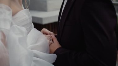 Damat ve gelin el ele tutuşuyor. Yeni evlilerin el ele tutuşması. Düğünlerinde nazikçe el ele tutuşan bir çift.