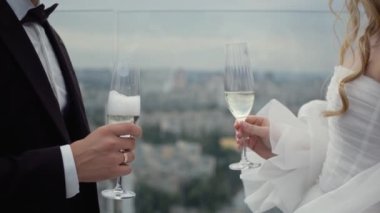Şampanya kadehleri olan genç ve güzel bir çift. Yeni evliler, gelin ve damat kadeh tokuşturuyor. Şehrin arka planında bir çift var..