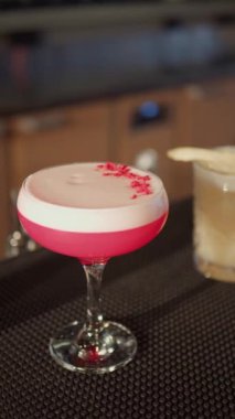 Bar tezgahında pembe kokteyl. Dikey video.