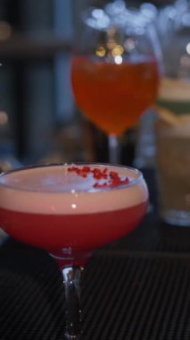 Profesyonel bir barmen, bir barda veya disko kulübünde müşteriler için pembe alkollü kokteyl hazırlar. Dikey video.