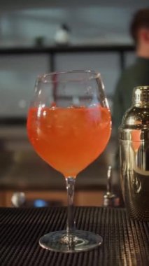 Tezgahta Aperol Spritz kokteyli var. Bulanık bir arka planda sprey kokteyli. Dikey video.
