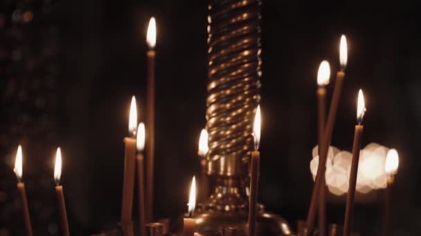 在东正教教堂点着蜡烛蜡制的蜡烛在黑暗中在教堂的黑暗中燃烧 教堂里的蜡烛在一个巨大的金烛台上燃烧 — 图库视频影像