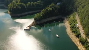 Yaz mevsiminde güpegündüz göl manzaralı tekneler. Video, daha yüksek bir irtifada bir drondan çekilmiş ve kamera yukarıdan görüntü almak için aşağıya bakıyor..