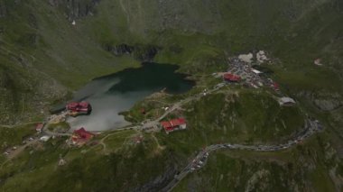 Romanya 'nın Transfagarasan yolundaki Balea Gölü' nün insansız hava aracı görüntüleri. Video gölün yukarısından çekilmiş. Kamera gölün, kulübelerin ve kavisli yolun üst görüntüsü için eğilmiş..