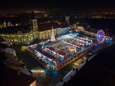 Sibiu şehir merkezinin Noel Fuarı 'yla çekilmiş peyzaj fotoğrafçılığı. Gün batımında şehir yıldırımı açıkken bir drondan çekilmiş. Romanya 'nın Sibiu kentinin manzarasına kuşların bakışı.