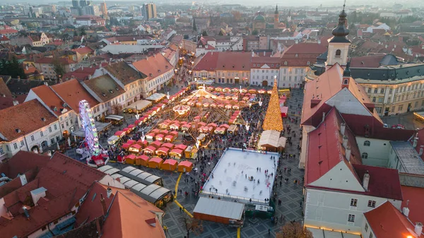 Sibiu şehir merkezinin Noel Fuarı 'yla çekilmiş peyzaj fotoğrafçılığı. Gün batımında şehir yıldırımı açıkken bir drondan çekilmiş. Romanya 'nın Sibiu kentinin manzarasına kuşların bakışı.