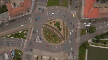 Aerial view of a busy roundabout intersection. Video was shot from a drone, with camera tilted downwards for a top view over the busy intersection.