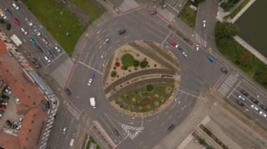 Aerial view of a busy roundabout intersection. Video was shot from a drone, with camera tilted downwards for a top view over the busy intersection.