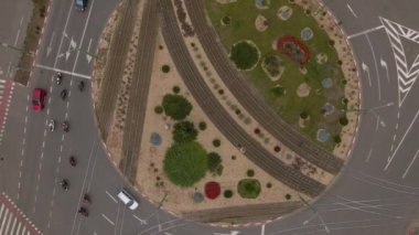 Aerial view of a busy roundabout intersection. Video was shot from a drone, with camera tilted downwards for a top view over the busy intersection.