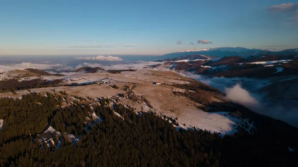 Landscape photography of mountains with clouds in a valley shot from a drone at sunset in the winter season. Aerial photography of mountains at sunset