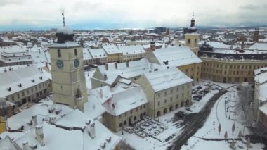 Romanya 'nın Sibiu kentinin ortaçağ şehir merkezine kışın günbatımında hava manzarası. Görüntüler, eski kasaba binalarının sinematik görüntüsü için ileri doğru uçarken düşük irtifadaki bir İHA 'dan çekildi..