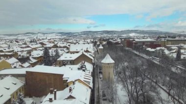 Romanya 'nın Sibiu kentinin insansız hava aracı videosu. Görüntüler, alçak irtifadaki bir drondan, kamera seviyesinde bir panorama için çekildi. Kış mevsiminde, manzarada ortaçağ savunma kulesi vardı..