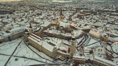 Romanya 'nın Sibiu kentinin ortaçağ şehir merkezine kışın günbatımında hava manzarası. Görüntüler yüksek irtifadaki bir İHA 'dan, ileri doğru uçarken ve kamerayla irtifa düşürürken çekilmiş..