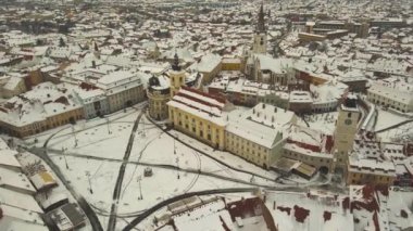 Aerial view of the medieval city center of Sibiu, Romania in winter at sunset. The footage was made from a drone at a higher altitude with the camera lowered for a top shot of the historic city center