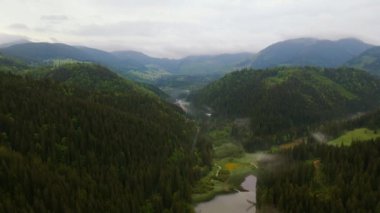 Romanya 'daki Kızıl Göl' ün görüntüsü bir drondan çekilirken, gölün üzerinden yavaşça ve sinematik bir şekilde, yüksek irtifada, manzarayı gözler önüne sermek için kamera ile çekiliyor..