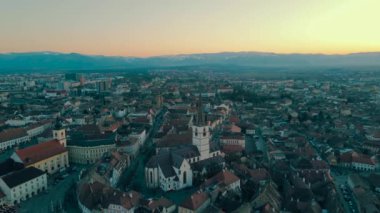 Romanya 'nın Sibiu kentinin ortaçağ kent merkezinin görüntüleri. Video, Katedral 'in yörüngesinde uçarken, panoramik bir görüntü için kamera seviyesiyle gün batımında bir İHA' dan çekildi..